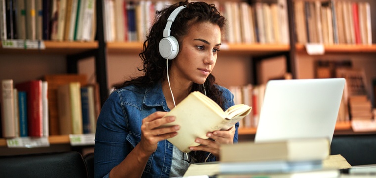 Studentin vor Laptop in Bibliothek