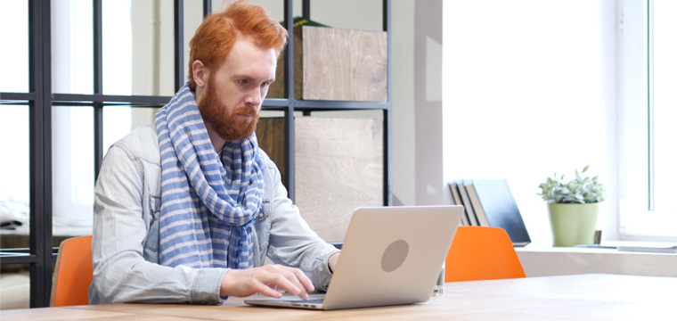 Ein Mann sitzt an seinem Laptop und formuliert den Schlusssatz seiner Bewerbung.