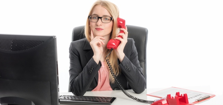 Eine Frau sitzt am Schreibtisch und telefoniert.