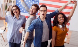 Eine Gruppe junger Studenten jubelt vor einer US-Flagge.